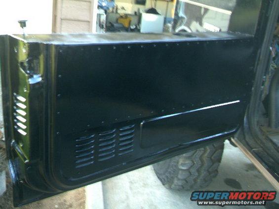 black interior door panel with rivets and vents, tire visible