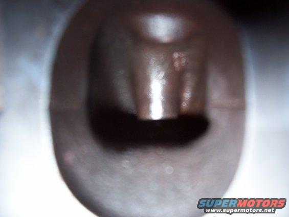 Close-up of a dark, metallic engine component with a central protrusion and a dark opening
