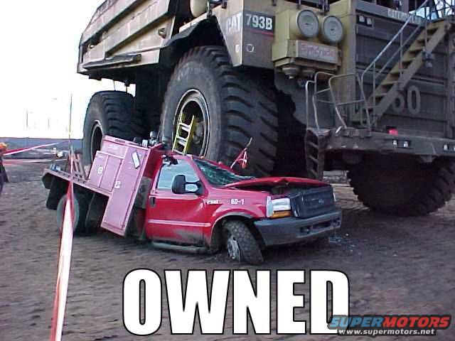 red pickup truck crushed under a massive mining truck