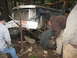 1990 Ford Bronco - Three people work on a damaged truck in a wooded area, with one person holding a tire.