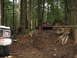 1990 Ford Bronco - Two off-road vehicles navigate a challenging muddy trail through a dense forest.