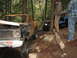 1990 Ford Bronco - Two off-road vehicles are stuck in a wooded area, with people attempting to free them.
