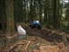 1990 Ford Bronco - Off-road vehicles navigate a challenging muddy terrain in a dense forest environment.