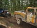 1990 Ford Bronco - Two vehicles are seen on a muddy forest trail, one a heavily damaged pickup truck and the other an off-road buggy.
