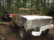 1990 Ford Bronco - A heavily damaged pickup truck navigates a muddy forest trail, followed by another off-road vehicle.