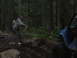 1990 Ford Bronco - Two men use a rope to pull a blue SUV out of the mud in a forest setting.