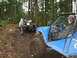 1990 Ford Bronco - Two off-road vehicles are seen in a muddy forest, one appears to be winching the other.