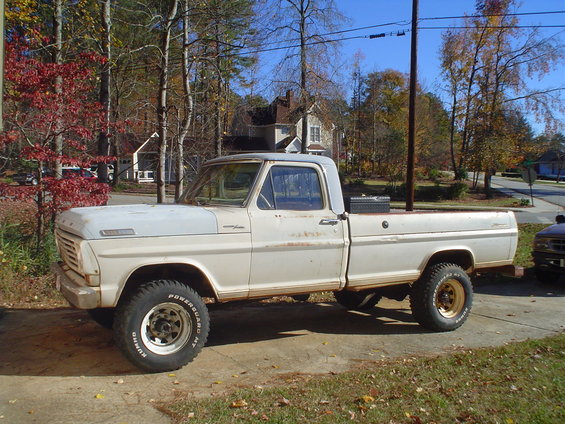 White Ford F-Series pickup truck parked in a driveway, lifted with off-road tires
