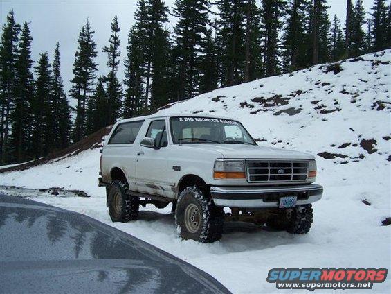 1996 Ford Bronco parked in snow with trees and a snowy hill in the background. "2 BIG BRONCOS 4X4 CLUB" sticker on windshield