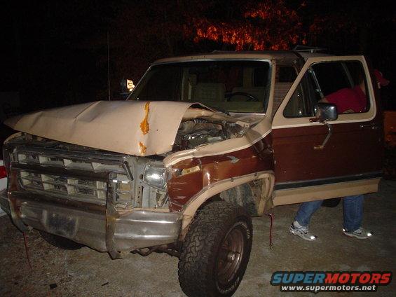 Damaged brown and tan 1980s SUV with crumpled hood and open driver's door