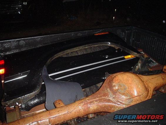 Rusty rear axle and black fender flare loaded in truck bed