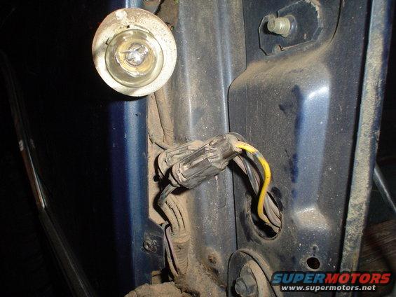 Blue vehicle's rear tail light wiring and bulb socket, dusty and disconnected
