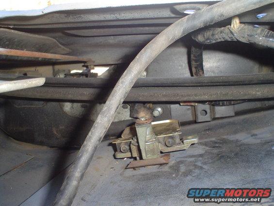 Close-up of a tailgate latch mechanism with cables and hoses