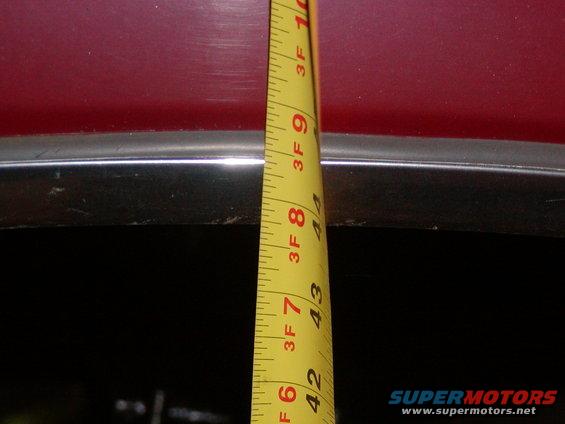 Red vehicle body with chrome trim measured by tape measure