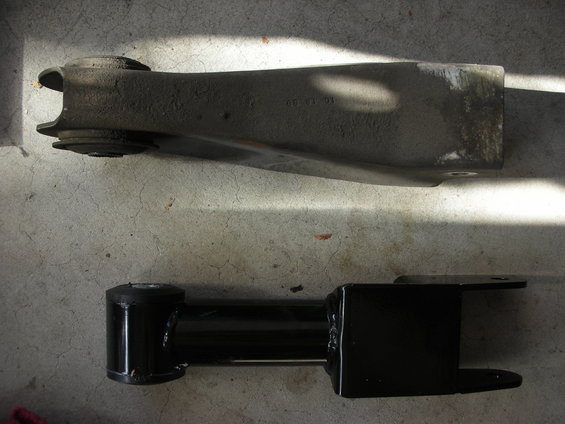 Old and new suspension control arms on concrete