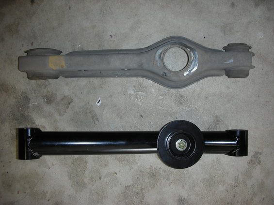 Old gray control arm above new black control arm with a circular mount
