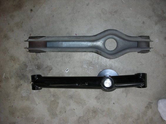 Two suspension control arms, one old and one new, on a concrete floor
