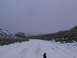 2003 Ford Ranger - A person stands on a snow-covered road winding through a mountainous landscape under a cloudy sky.