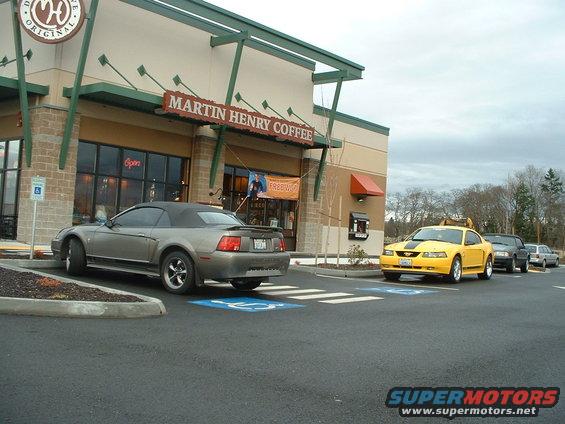 Gray Ford Mustang convertible parked in handicap spot, yellow Ford Mustang coupe in line