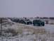 2003 Ford Ranger - Multiple SUVs and trucks drive in a convoy on a snow-covered road under a cloudy sky.