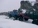 2003 Ford Ranger - Two modified off-road vehicles navigate a snowy terrain with large rock formations in the background.