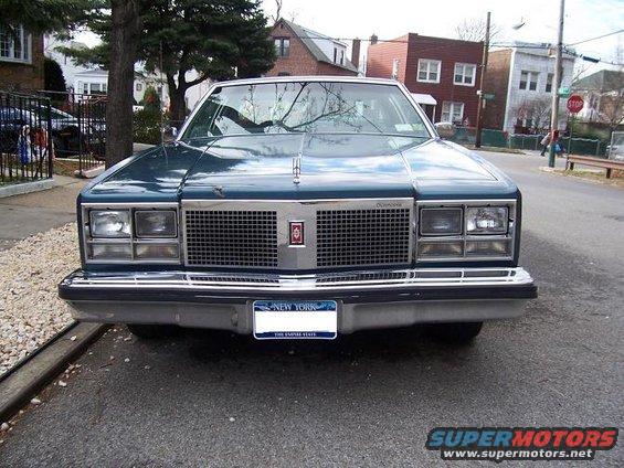 Front view of a dark blue Oldsmobile Delta 88 parked on a residential street