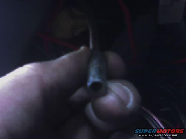 hand holding a metal electrical connector with wires behind it