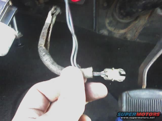 Hand holding a disconnected wiring harness connector inside a vehicle