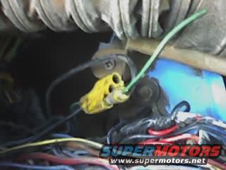 Close-up of a yellow electrical connector with a green wire attached to a vehicle wiring harness
