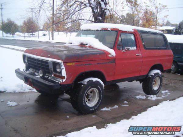 Red Ford Bronco with snow on it, parked outside