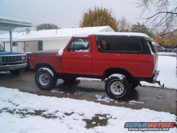 Red 1978 Ford Bronco II with a black top, parked in snow, side view