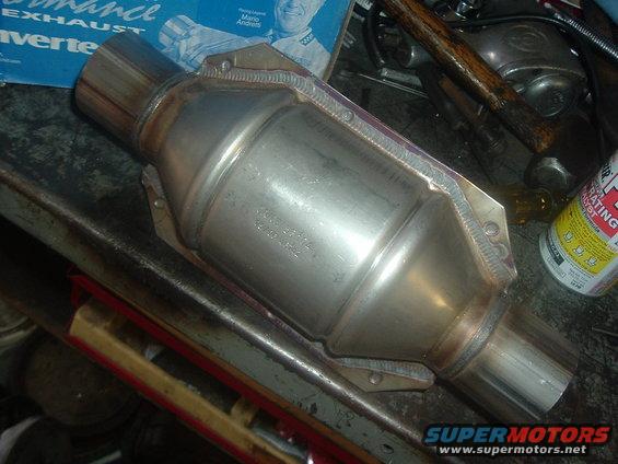 Catalytic converter with part number stamped on its side, resting on a workbench