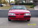 1990 Ford Mustang - A red 1990 Ford Mustang is parked in front of a house, with another vehicle in the background.