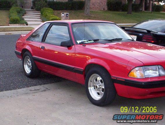 Red 1990 Ford Mustang coupe with chrome wheels parked on driveway