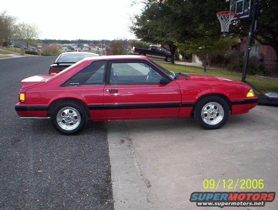 Red 1990 Ford Mustang coupe, side view, aftermarket wheels, slight damage on front bumper