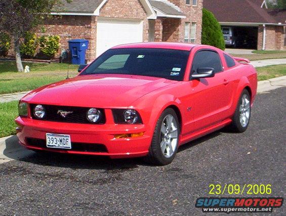 Red 2006 Ford Mustang parked on street in front of a house