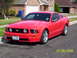 2006 Ford Mustang - A red 2006 Ford Mustang is parked in a driveway on a sunny day.