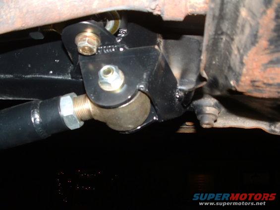 Close-up of a black metal suspension linkage with a ball joint and bolts