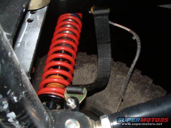 Red coilover shock absorber and part of a tire with visible tread