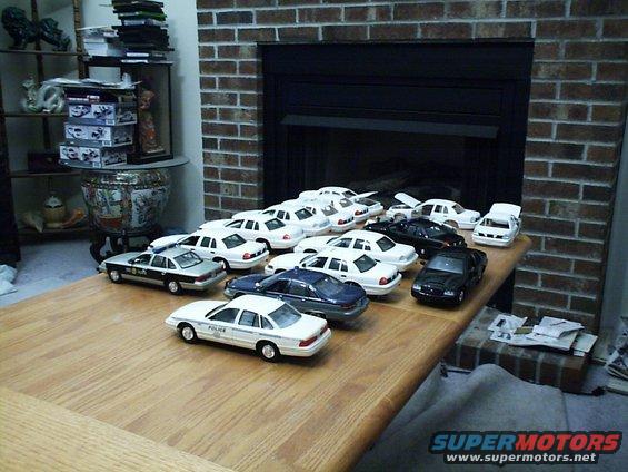Collection of model cars on a wooden table in front of a fireplace