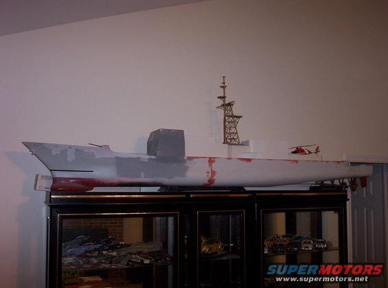 Model ship on display above a cabinet with model cars inside