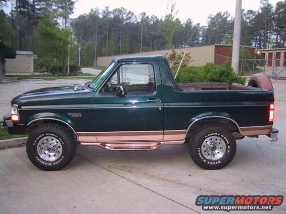 Green Ford Bronco with a copper stripe and running boards, seen from the side