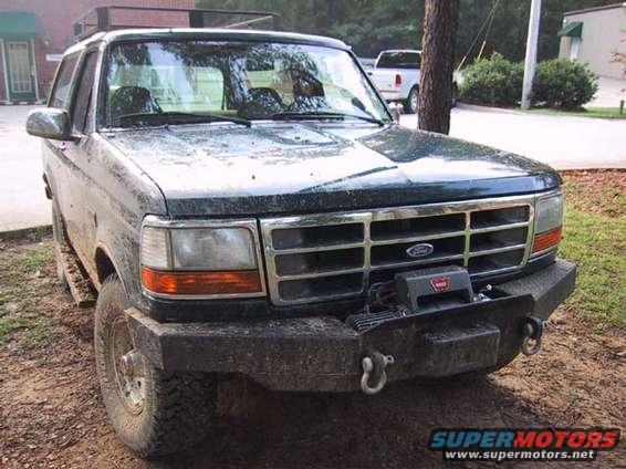 1995 Ford Bronco front view, dark green, dirty, with custom bumper and winch