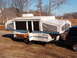 1975 Ford Bronco - A pop-up camper is parked in a residential yard, attached to a dark SUV.