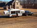 1975 Ford Bronco - SUV towing a pop-up camper trailer in front of a large brick house.