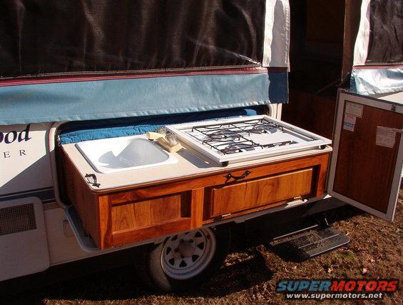 Pop-up camper exterior with sink, stove, and wooden cabinets