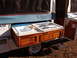 1975 Ford Bronco - Exterior view of a pop-up camper's slide-out kitchen unit a sink and a propane stove.