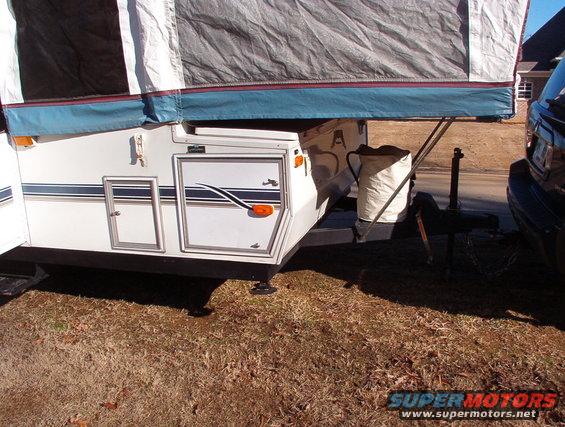 Pop-up camper with blue trim and stripes, hitched to a dark SUV