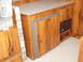 1975 Ford Bronco - Interior view of a camper showing wood paneling, a folded cushion, and a refrigerator unit.