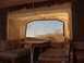 1975 Ford Bronco - The interior of a pop-up camper shows a dinette area with a table and seating, looking out a large window.